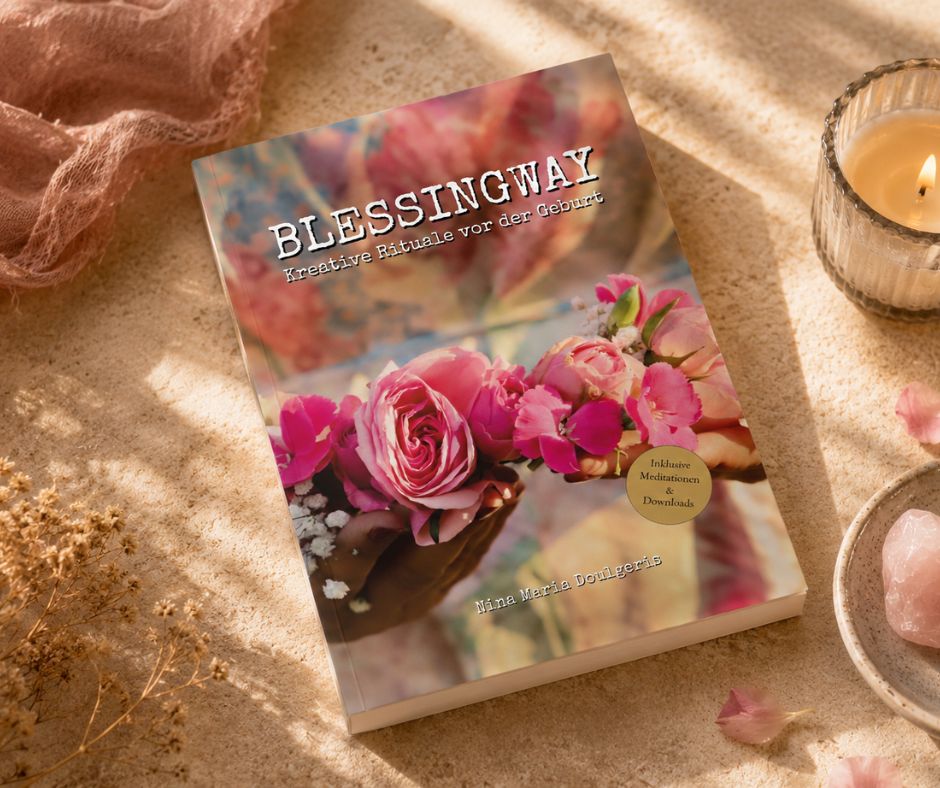 Das Buch "Blessingway" liegt auf einem hellen Leinentuch mit Ritualgegenständen wie Kerzen und Steine