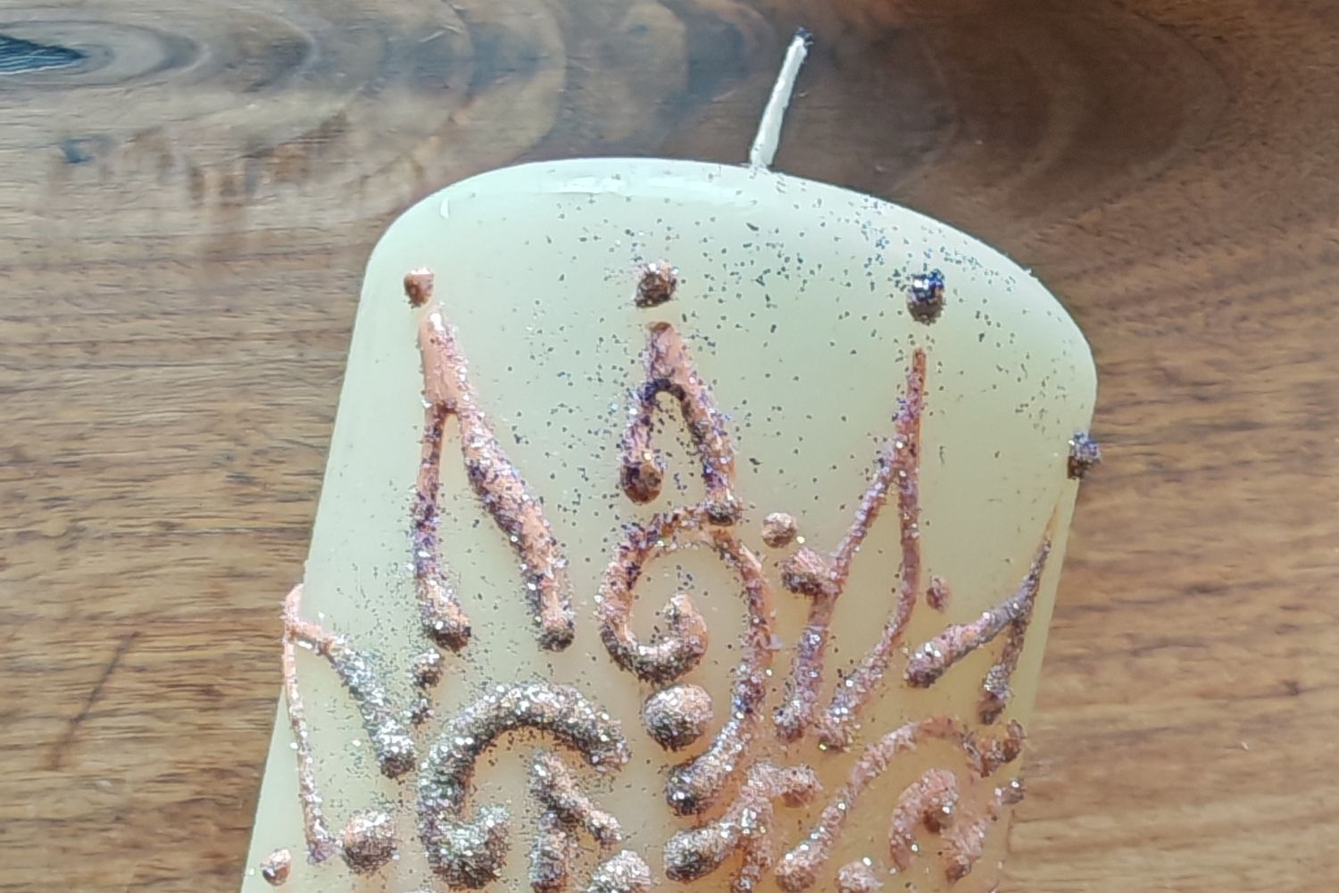 Eine weiße gestaltete Kerze vor einem Holztisch im Hintergrund als Zeichen für die Rauhnächte