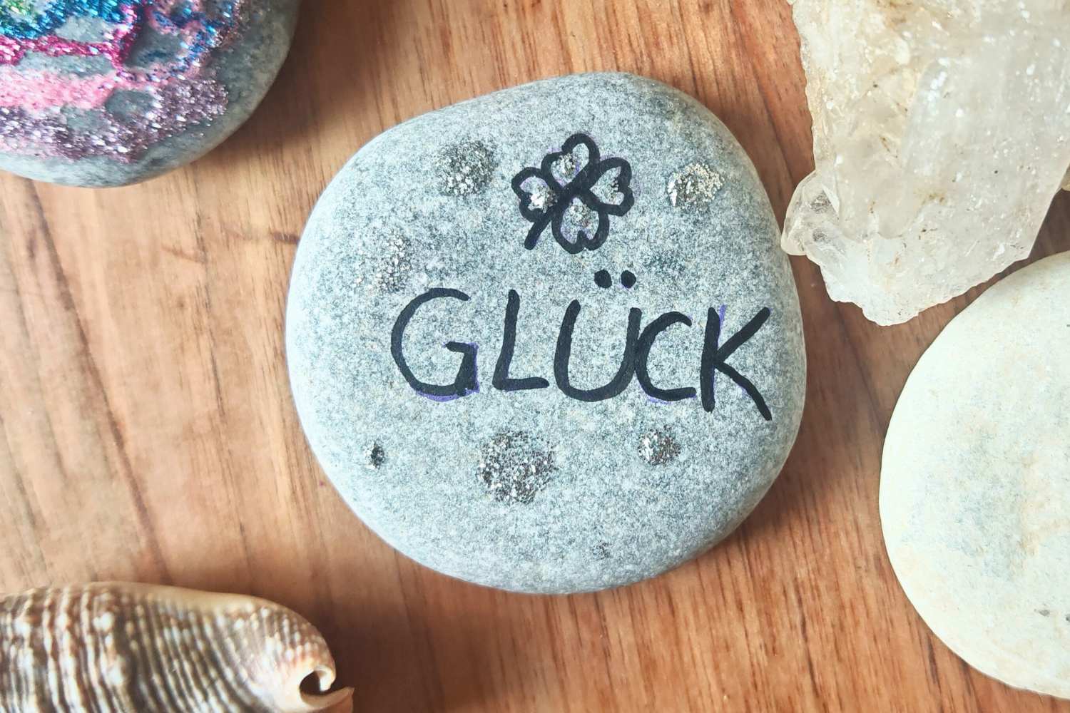 Glücksstein mit Schriftzug "Glück" neben Kristall und Muschel - Ritual für das neue Jahr