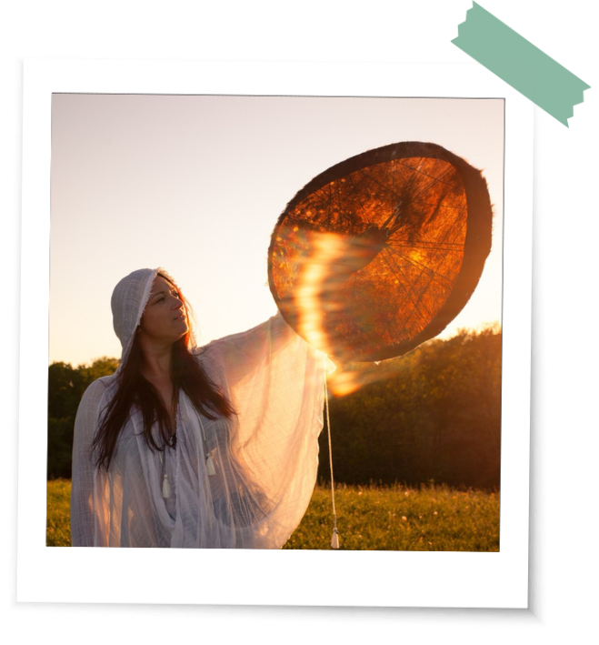 Beltane und Ritualbilder Licht Trommel Bei einem Beltane Ritual scheint magisches Licht durch die Pferdetrommel einer Frau im weißen Gewand.