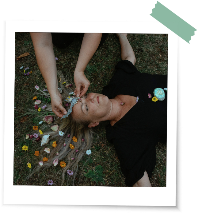 Frau liegt auf der Erde ihr Haar wird rituell geschmückt