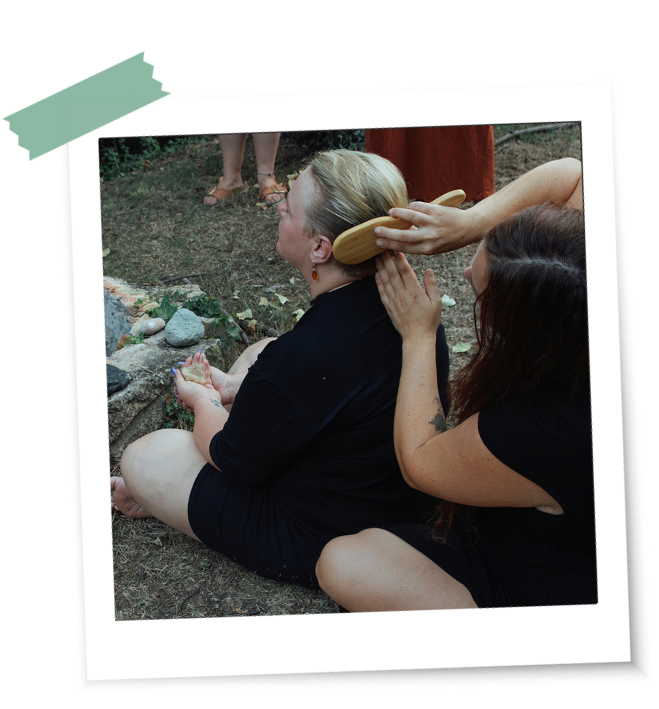 Eine Frau kämmt einer anderen Frau die Haare vor dem Feuer sitzend