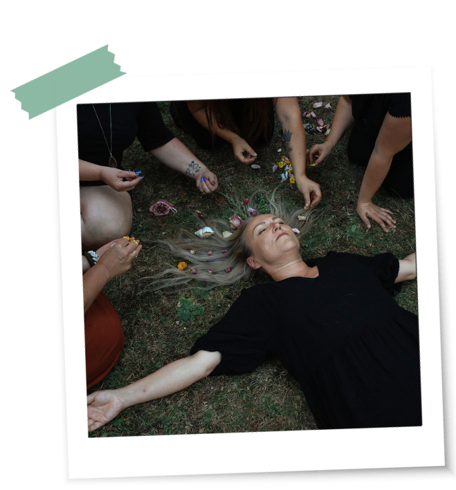 Frauen schmücken die Haare einer auf der Erde liegenden Frau im Ritual