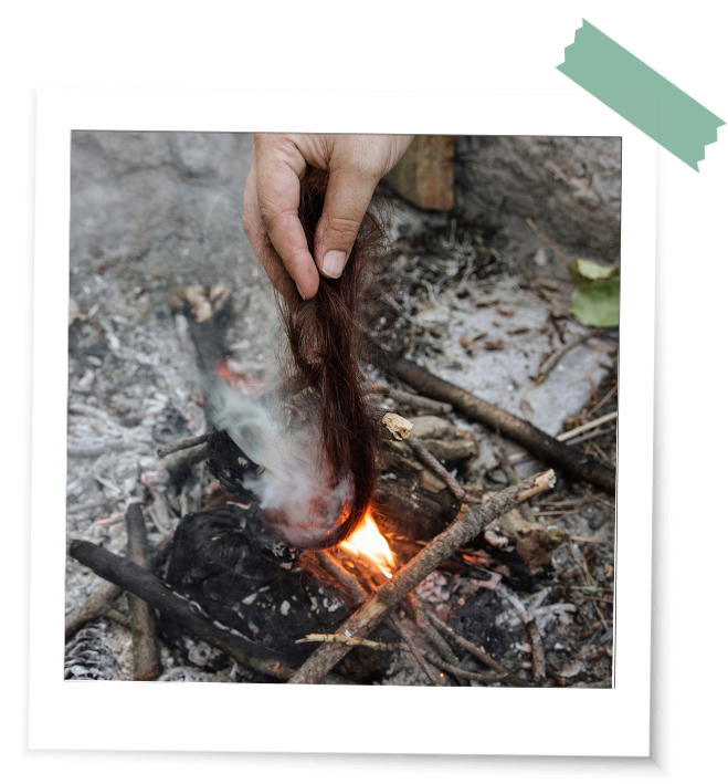 Hand verbrennt im Feuer einen Strang Haare in einem Ritual