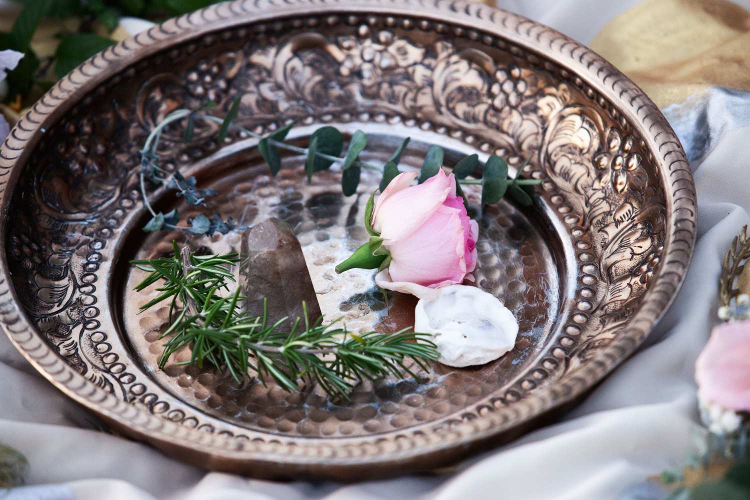 Hände gestalten ein Ritual mit Blumen und Naturmaterlialien - Symbol für kreative Ritualpraxis