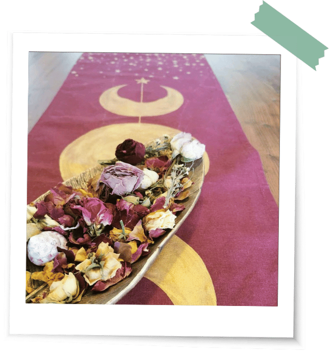 Dunkelrotes Tuch mit goldenen Mondphasen und Sternen liegt geschmückt auf einem Holztisch als eines der ersten LaLuna-Ritualtücher