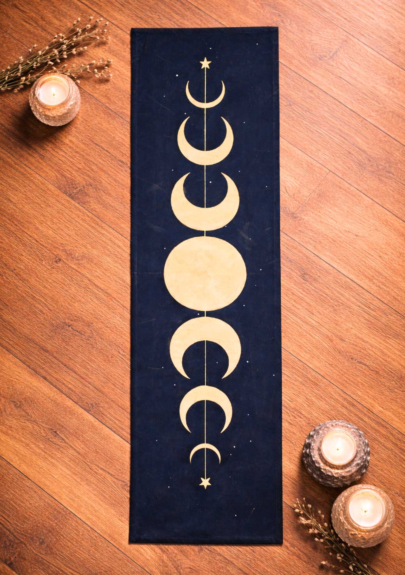 ein dunkelblaues längliches LaLuna-Rituatuch mit goldenen Monden liegt auf einem Holzboden mit Kerzen