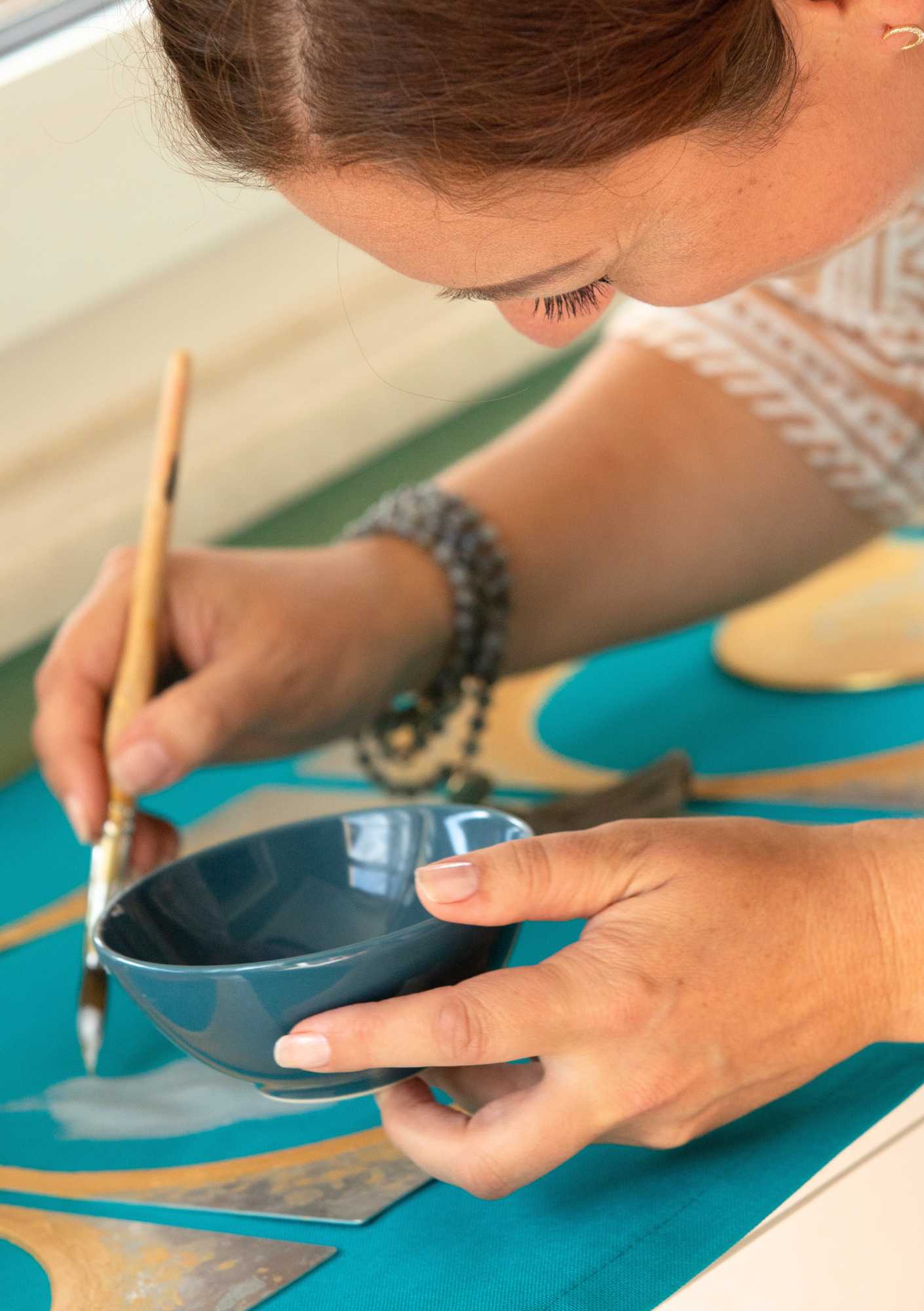 Nina Maria Doulgeris bemalt ein persönliches LaLuna-Ritualtuch mit Pinsel und goldener Farbe