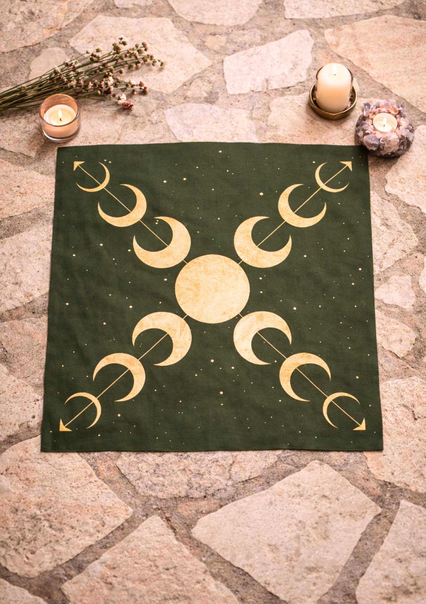 ein dunkelgrünes LaLuna-Ritualtuch mit goldenen Mondphasen liegt auf einem Steinboden mit Kerzen und Kräutern