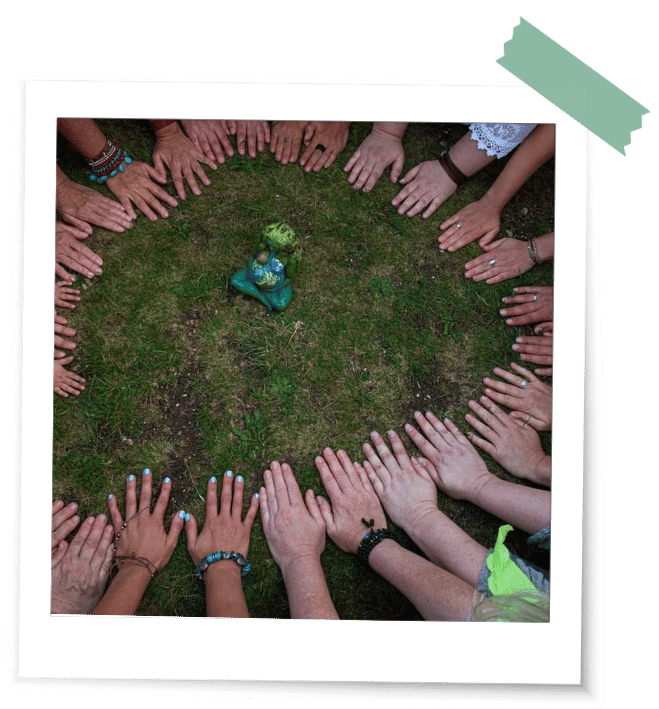 Was ist ein Ritual Hände Viele Frauenhände am Boden im Kreis um eine kleine Statue als Erdgöttin in einem Ritual auf einer Wiese