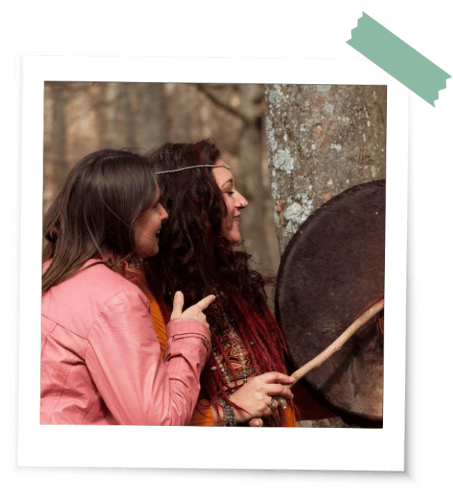 Was ist ein Ritual Trommel Zwei Frauen trommeln im Wald vor Bäumen mit einem Trommelschlegel auf eine Pferdetrommel